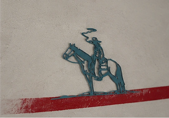 Close view of the teal cowboy on horseback, lasso raised, waiting on a thick red painted line